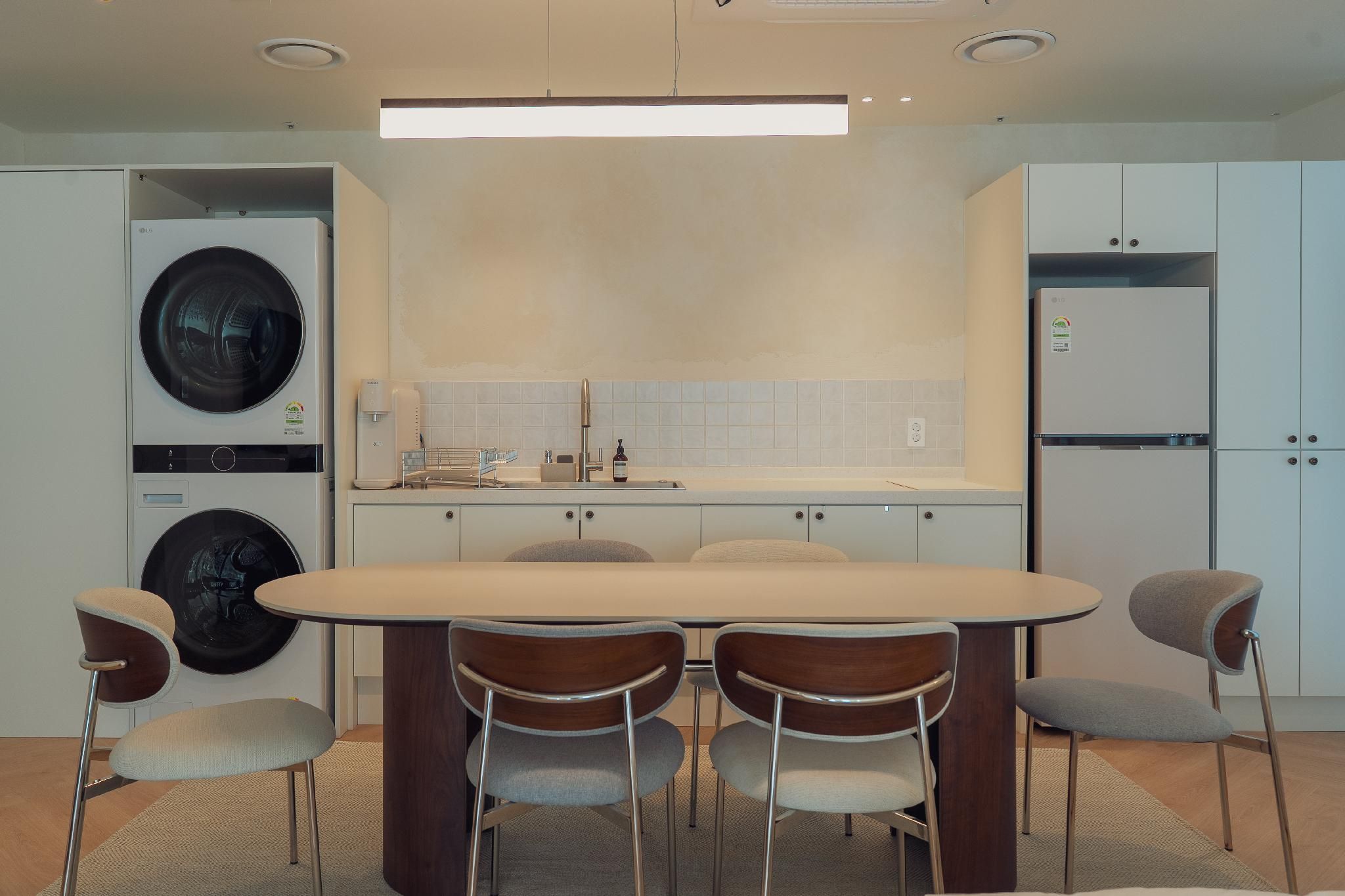 A modern kitchen with a central island, built-in appliances, and a dining area with chairs.