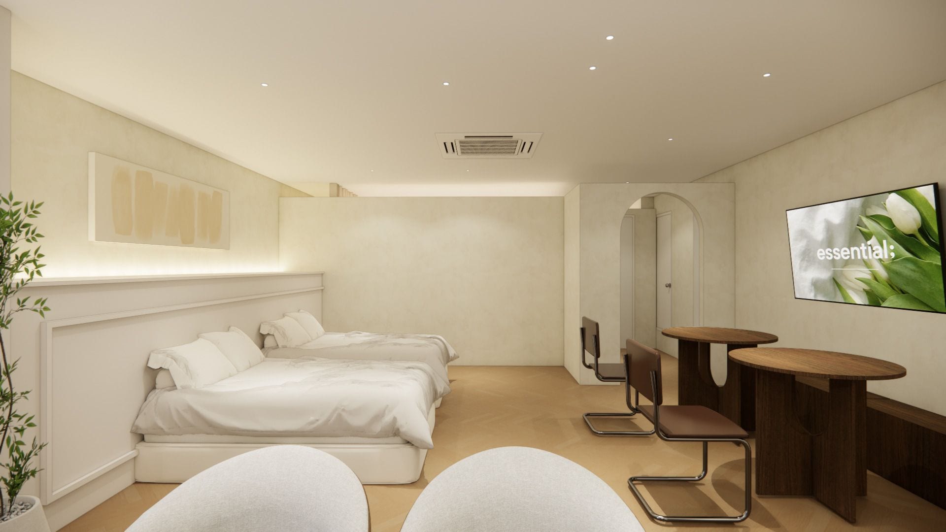 A modern hotel room with a bed, two chairs, a small table, a TV, and a plant.