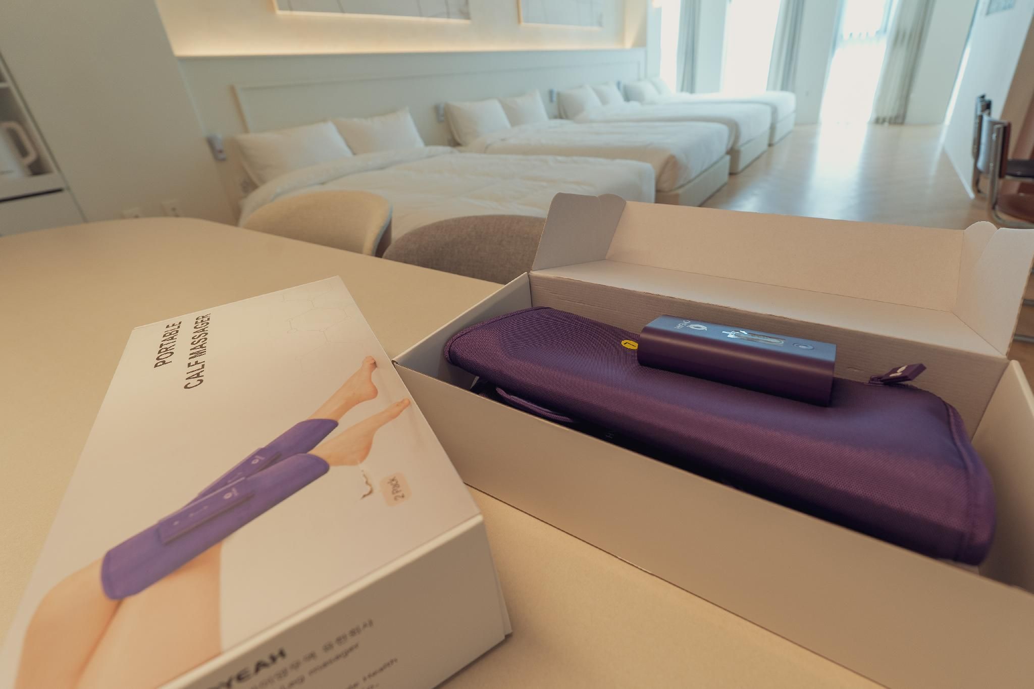 A bedroom with a bed, a bedside table, and a box containing a portable massage device.
