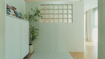 A room with a white cabinet, a potted plant, a window with frosted glass, and a speckled floor.