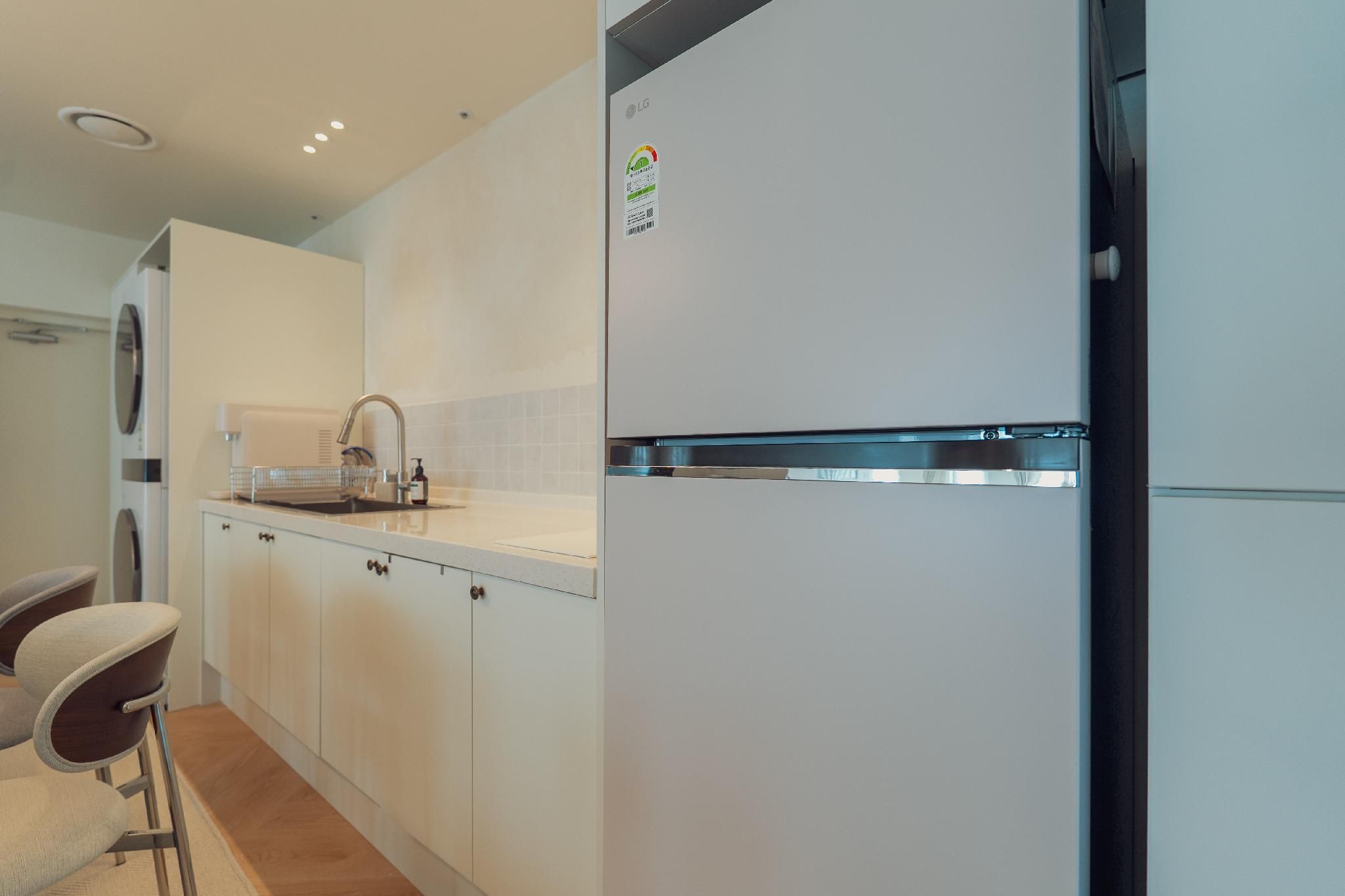 A modern kitchen with white cabinetry, a stainless steel refrigerator, and a built-in oven.