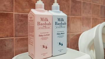 Dos productos para el cuidado del bebé, la loción Milk Baobab Baby y el jabón Baby Wash, sobre una superficie blanca frente a una pared de azulejos.