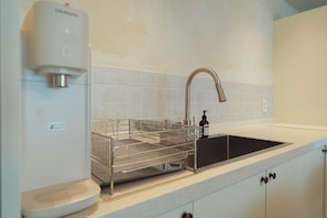 A kitchen with a stainless steel sink, a dish drying rack, and a soap dispenser. - The Villa 23 (Seoul)