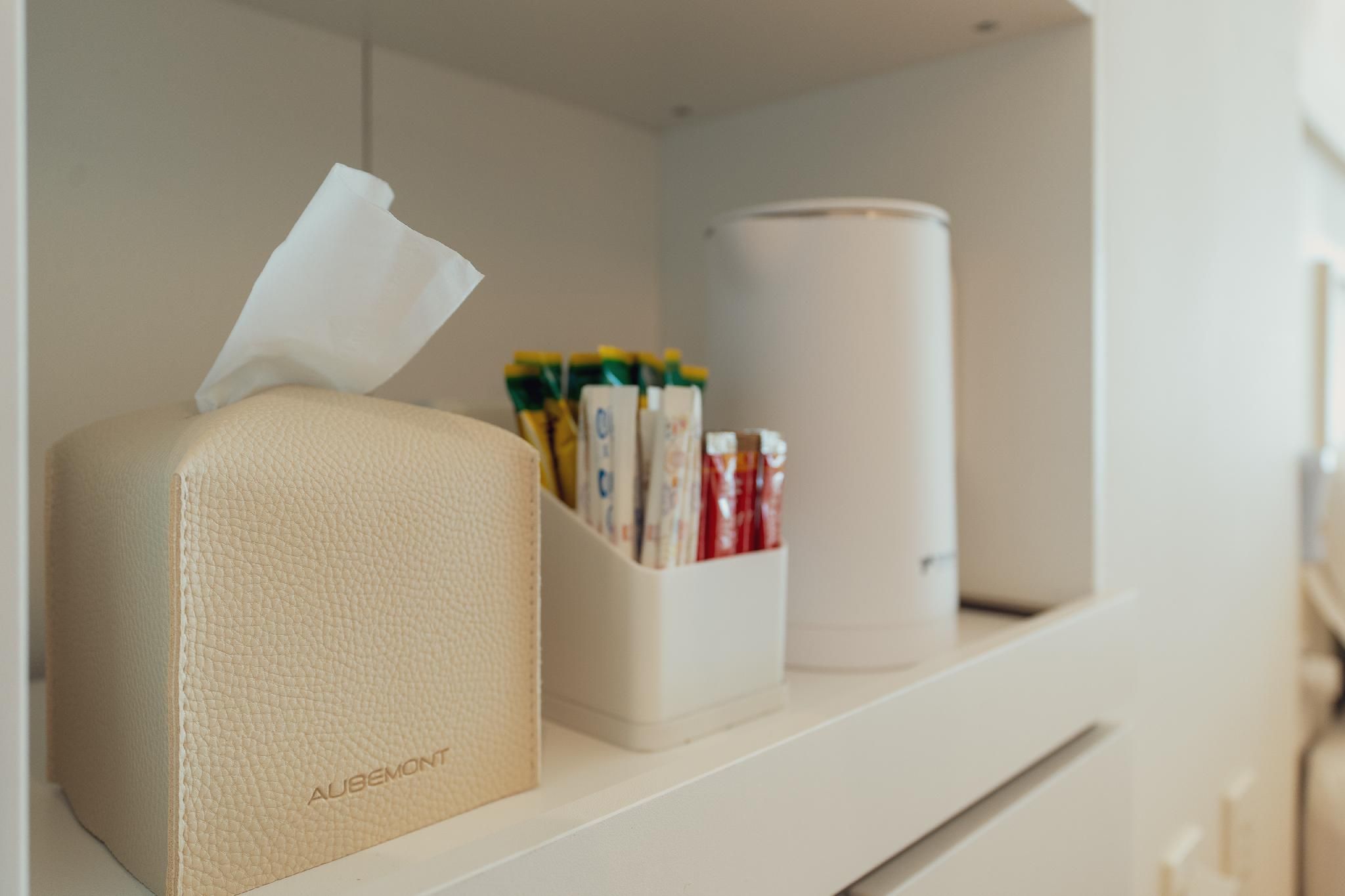 A shelf with a tissue box, a container holding various items, and a cylindrical object.
