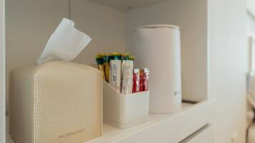 A shelf with a tissue box, a container holding various items, and a cylindrical object.