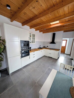 A kitchen with white cabinets, a built-in oven, and a wooden ceiling. - Ensueño Estate (Frontera)