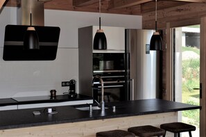 Eine moderne Küche mit schwarzem Arbeitsplatz, Edelstahlgeräten und Pendelleuchten.