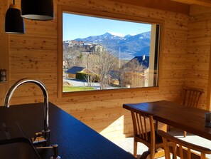 Ein Holzinterieur mit einem großen Fenster, einem Waschbecken und einem Esstisch.