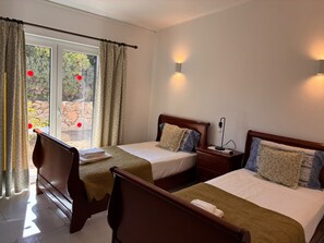 A hotel room with two beds, a window with curtains, a nightstand with a lamp, and a view of the outdoors. - Villa with heatable pool in Carvoeiro (Carvoeiro)