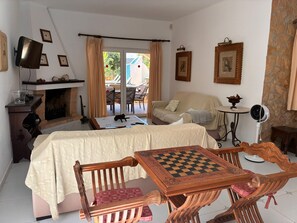 Una habitación acogedora con chimenea, una cama, una mesa con un tablero de ajedrez y vistas a una piscina al aire libre.