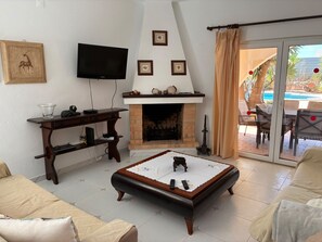 A living room with a fireplace, television, and outdoor patio. - Villa with heatable pool in Carvoeiro (Carvoeiro)