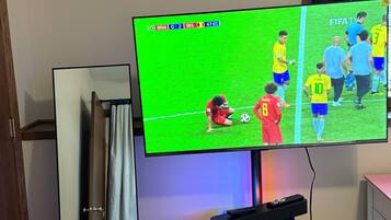 A television mounted on a stand with a remote control on a stand below it.