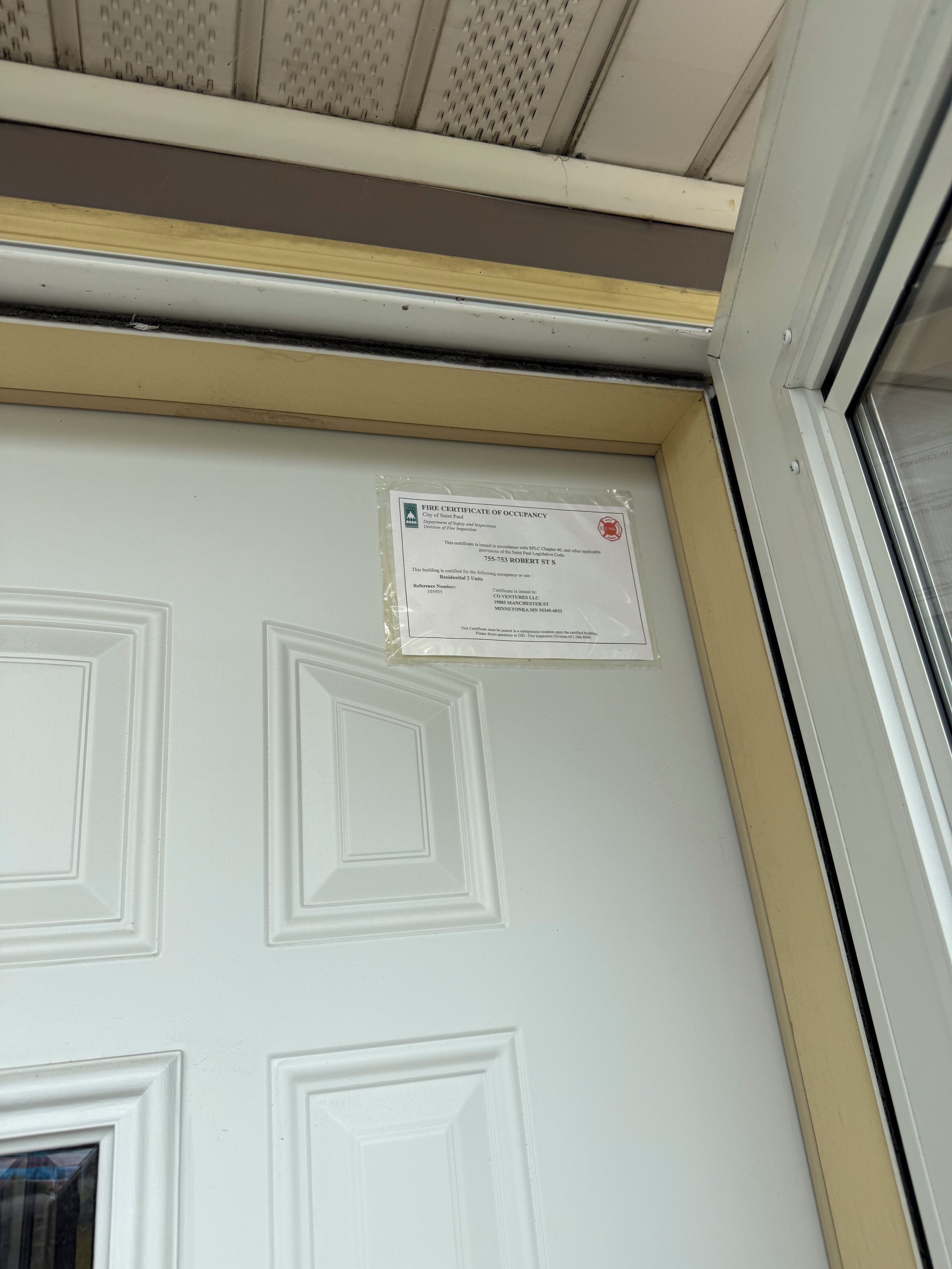 A white door with a fire safety certificate attached to it.
