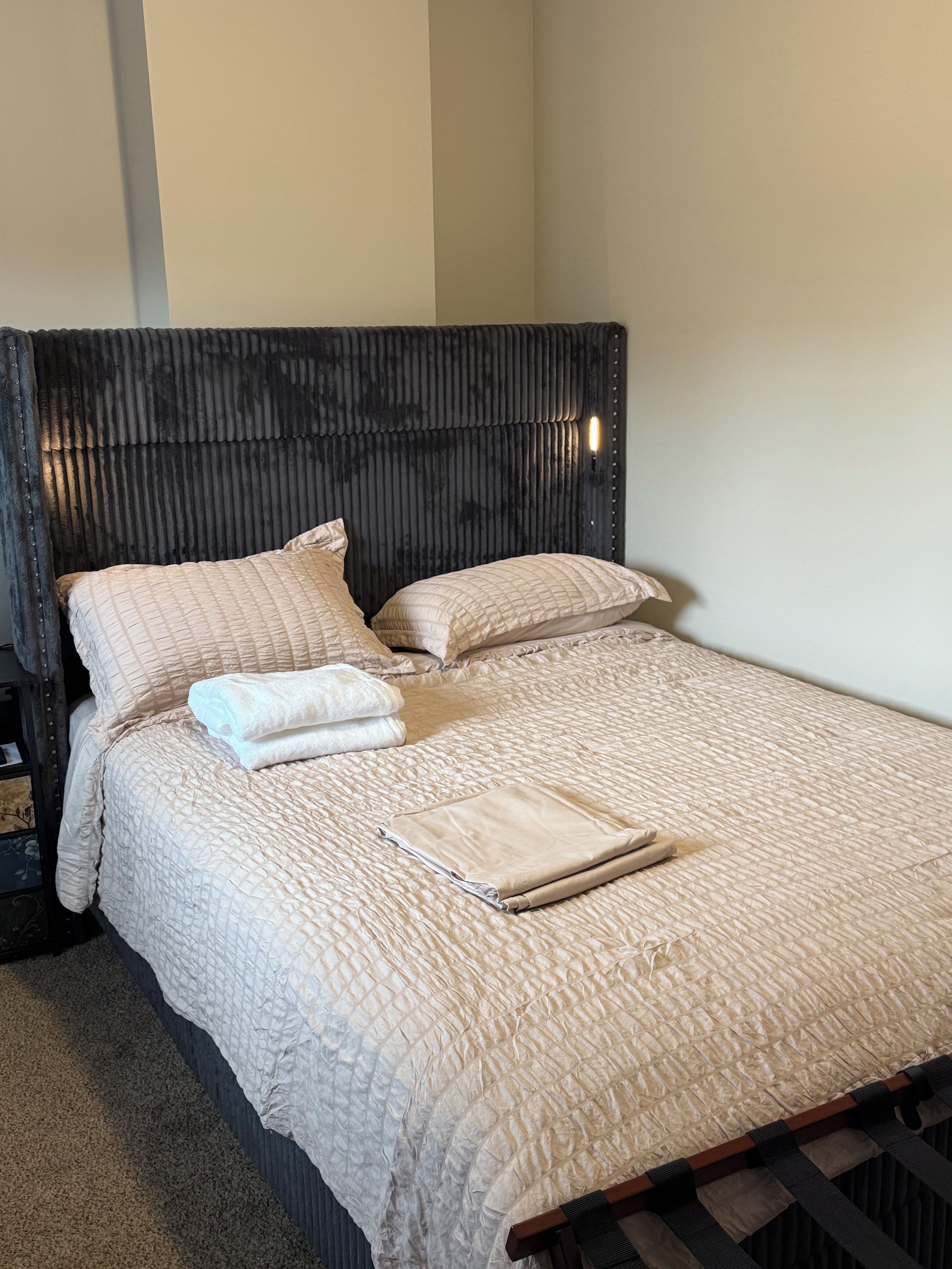 A neatly made bed with a quilted cover, pillows, and a folded blanket.