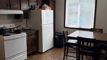 Une cuisine équipée d’une cuisinière, d’un réfrigérateur et de meubles de rangement en bois.