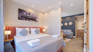 Een hotelkamer met een groot bed, een bank, een eettafel en een schilderij aan de muur.