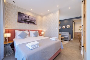 Ein Hotelzimmer mit einem großen Bett, einer Sitzecke, einem Esstisch und einem Bild an der Wand.