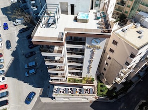 Un hotel con varios balcones, una piscina en la azotea y un letrero que indica que es un hotel.