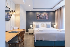 Habitación de hotel con cama, mesitas de noche, escritorio, una silla y una obra de arte colgada en la pared.