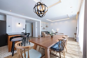 Een moderne eethoek met een houten tafel, stoelen en een centraal hanglamp.