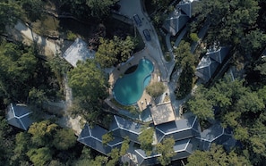 Vista aérea de un barrio residencial con piscina, rodeado de casas con diseños de tejados únicos.