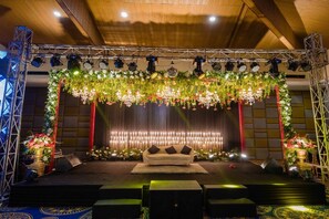 A stage with a sofa, floral decorations, and lighting equipment.