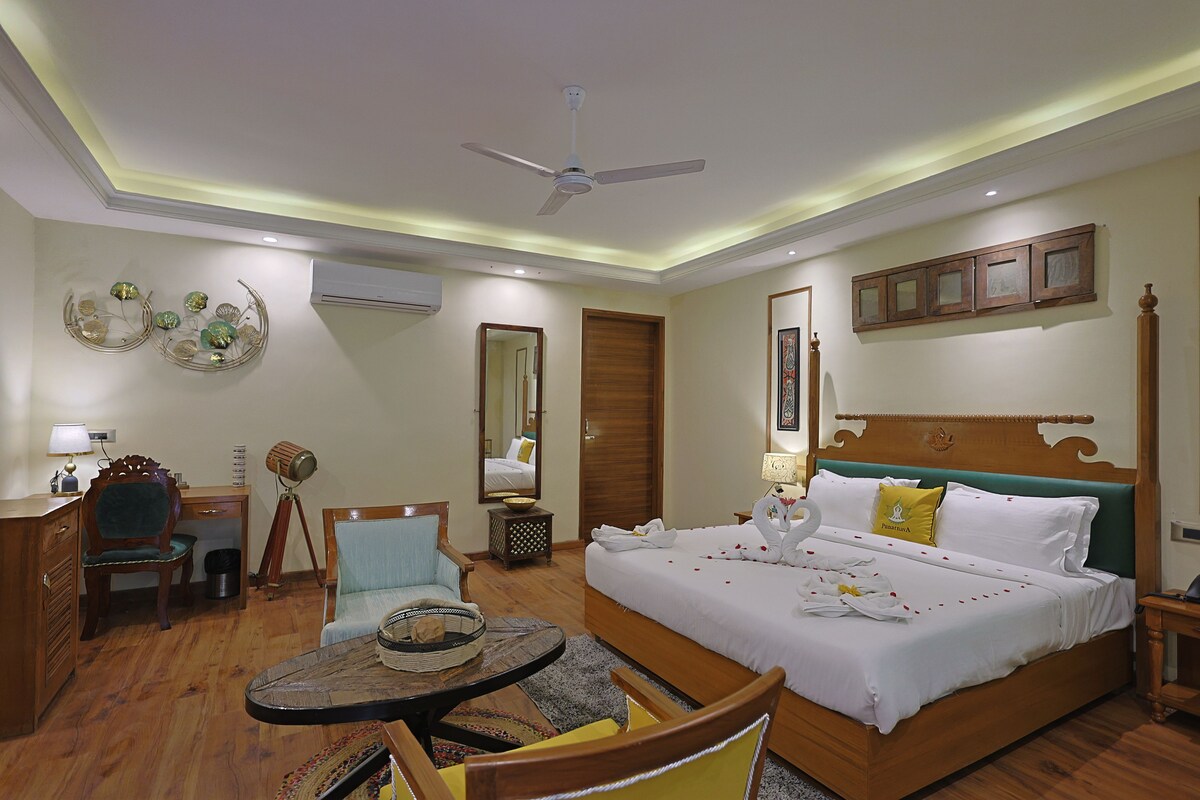 A hotel room with a bed, a desk, a chair, a small table, and a ceiling fan.