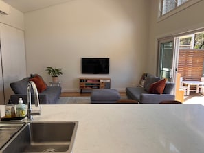 Ein modernes Wohnzimmer mit grauen Sofas, einem Flachbildfernseher und einem Holztisch.