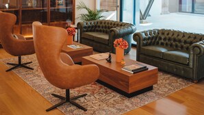 A modern living room with leather sofas, a wooden coffee table, and a glass cabinet with decorative items. - The Vinea Collection Hotel (Monção)