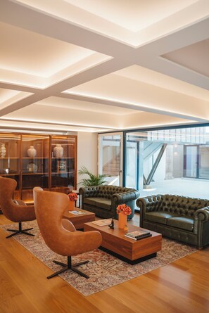 A modern living room with leather sofas, a wooden coffee table, and a glass cabinet with decorative items. - The Vinea Collection Hotel (Monção)