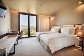 A hotel room with two beds, a desk, a chair, and a large window with a view. - The Vinea Collection Hotel (Monção)