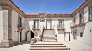 A courtyard with a central staircase leading to a door, flanked by buildings with balconies and windows.