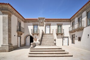 Un patio con una escalera central que lleva a una puerta, flanqueado por edificios con balcones y ventanas.