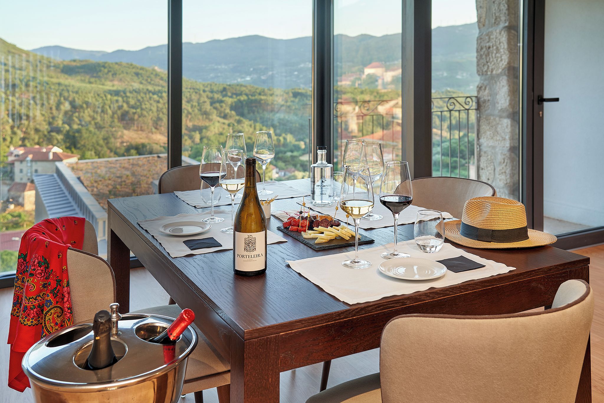 A dining table set for two with wine glasses, a bottle of wine, and a plate of appetizers.