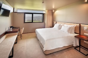 A hotel room with a large bed, a desk with a chair, a flat-screen TV mounted on the wall, and a window with a view of the outdoors. - The Vinea Collection Hotel (Monção)