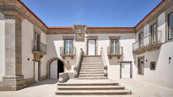 Un patio con una escalera central que lleva a una puerta, flanqueado por edificios con balcones y ventanas.