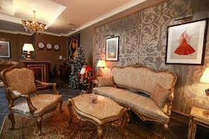 A traditional room with a sofa, armchairs, a coffee table, a chandelier, and a Christmas tree. - West Inn Palace Hotel (Baku)