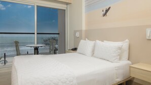 A hotel room with a large bed, a small table, and a view of the ocean. - Radisson Riviera Panama (Las Huacas)