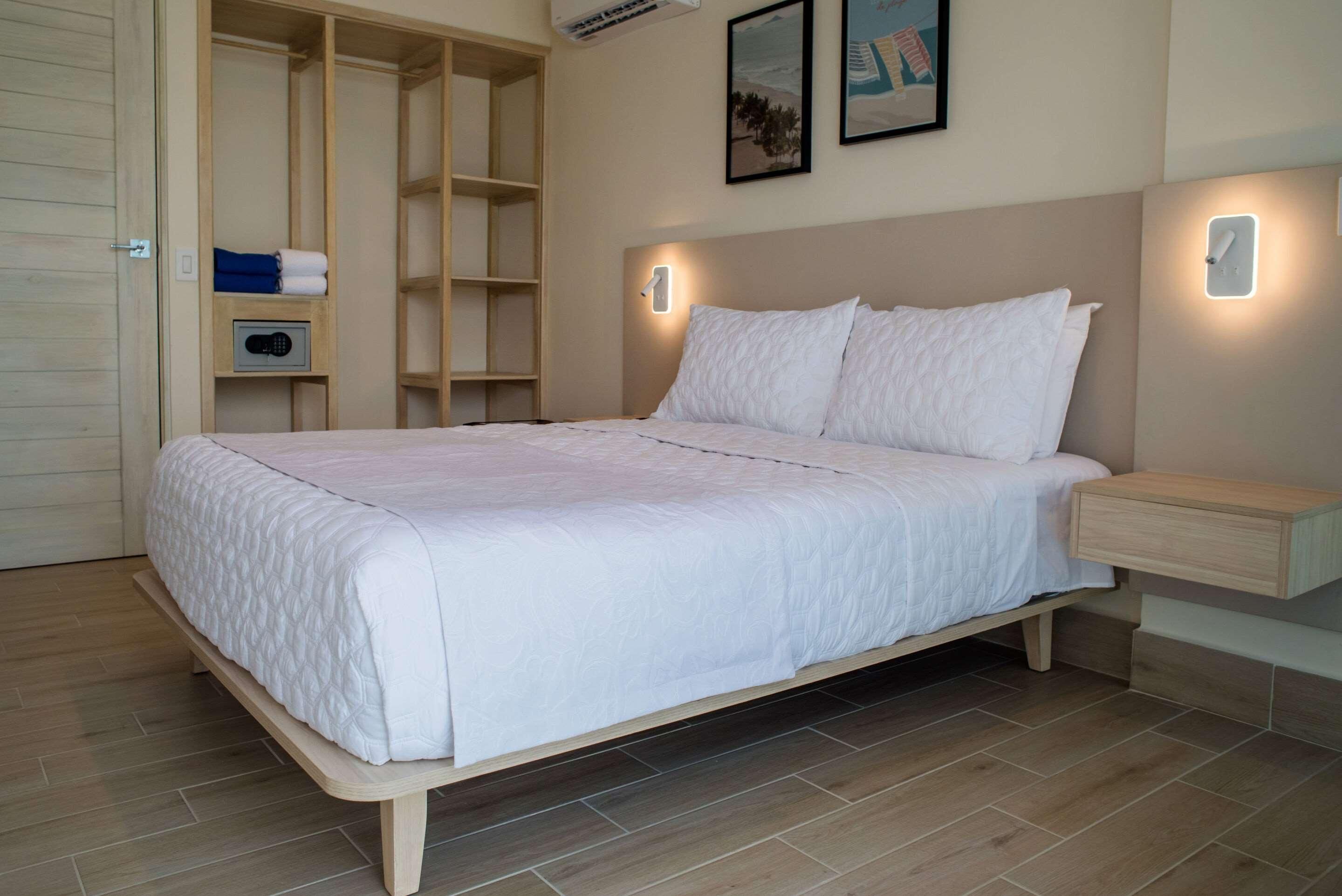 A bedroom with a bed, bedside tables, a wardrobe, and a wall-mounted air conditioning unit.