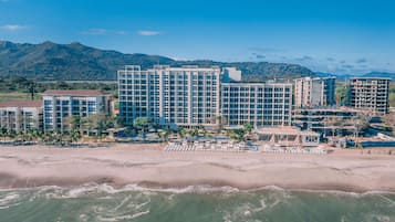 A beachfront hotel with multiple buildings, a sandy beach, and ocean waves.