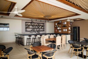 A restaurant with a bar area, wooden ceiling, and a variety of seating options including bar stools and tables.