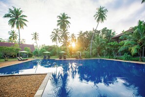 A swimming pool surrounded by palm trees and lounge chairs.
