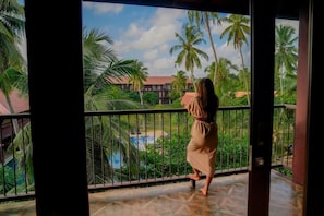 A person on a balcony with a view of a pool and palm trees. - Celestia Ayurveda Resort (Bentota)