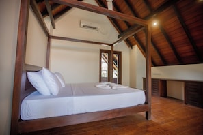Una cama con dosel con sábanas y almohadas blancas, techo de madera y un equipo de aire acondicionado en la pared.
