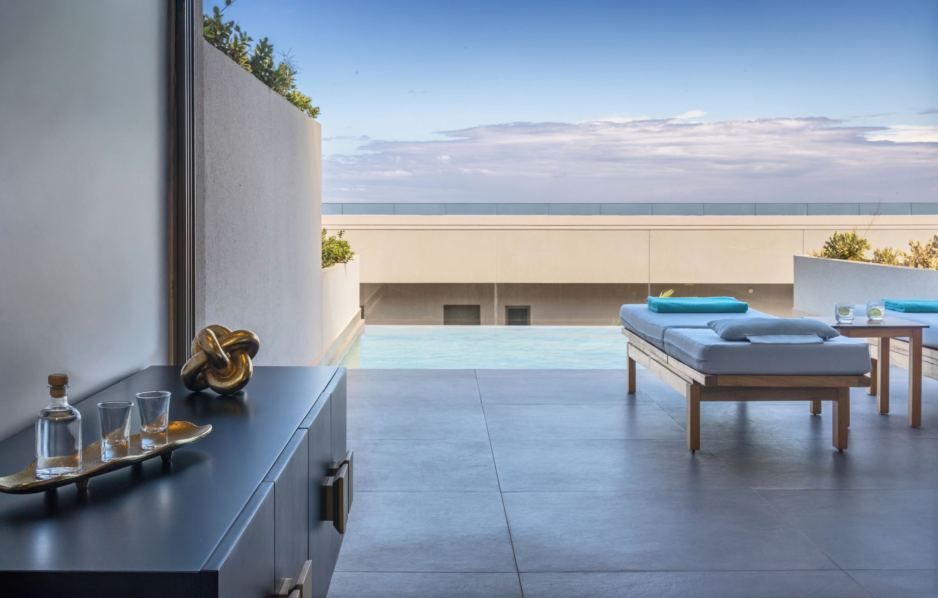 A modern rooftop terrace with a pool, a sofa, and a table.