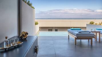 A modern rooftop terrace with a pool, a sofa, and a table.