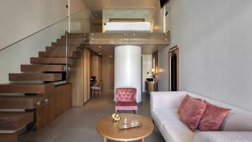 A modern interior with a staircase, a round wooden coffee table, a cushioned sofa, and a pink chair.