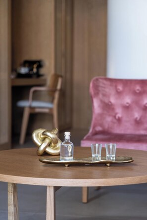 A round wooden table with a tray holding a glass bottle and three shot glasses. - Castello Boutique Suites By The Sea (Agios Nikolaos)