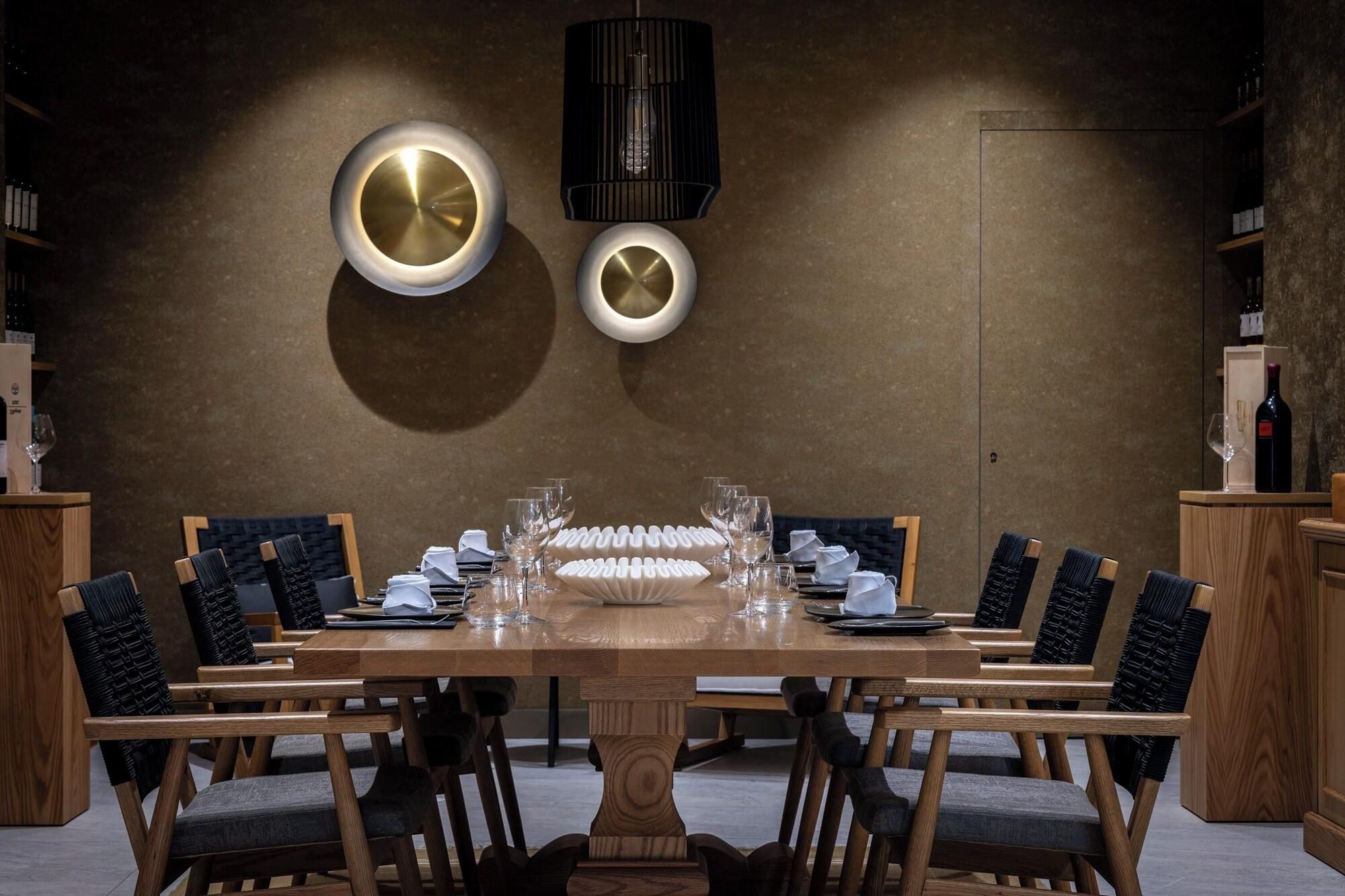 A dining area with a long wooden table set for a meal, surrounded by chairs with cushioned seats.
