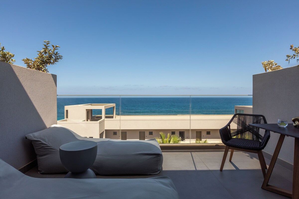 Un balcón con vista al mar, una mesa y una silla.